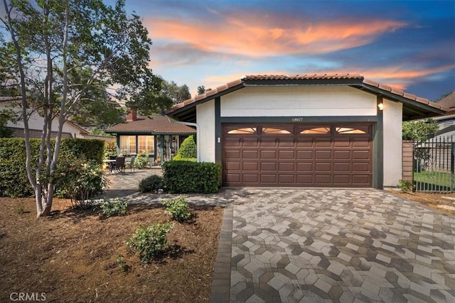 6807 Wilding Pl, Riverside, CA 92506 - view of front facade with driveway, an attached garage, a tiled roof, and stucco siding