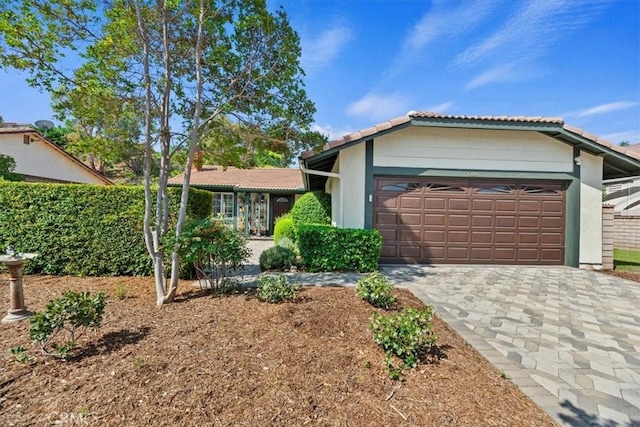 6807 Wilding Pl, Riverside, CA 92506 - ranch-style home with a tiled roof, an attached garage, decorative driveway, and stucco siding