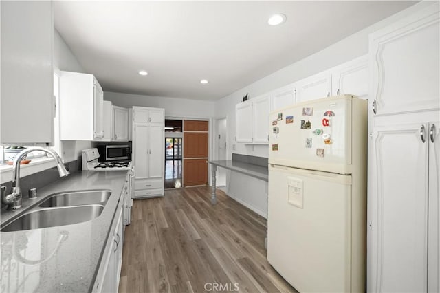1067 N Wilton Pl, Los Angeles, CA 90038 - kitchen with freestanding refrigerator, white cabinetry, recessed lighting, light wood finished floors, and stainless steel microwave