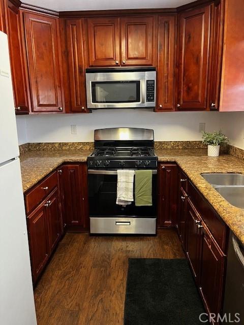 235 S 2nd St, Shandon, CA 93461 - kitchen featuring stainless steel appliances, reddish brown cabinets, dark wood-style floors, and dark stone countertops