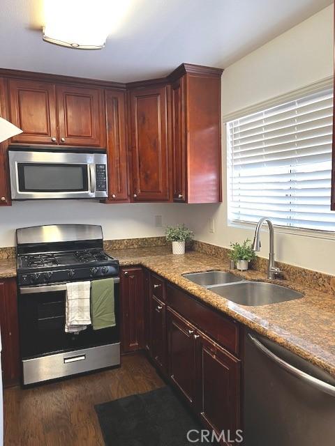 235 S 2nd St, Shandon, CA 93461 - kitchen with stainless steel appliances, dark wood finished floors, and reddish brown cabinets