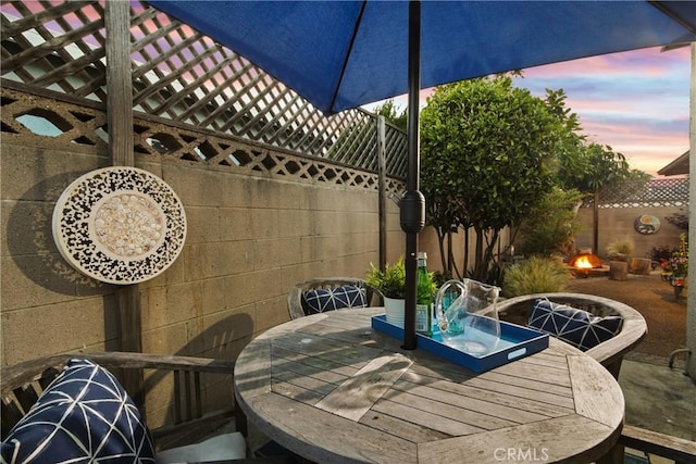 2283 Ximeno Ave, Long Beach, CA 90815 - patio terrace at dusk featuring outdoor dining space, an outdoor fire pit, a fenced backyard, and a patio