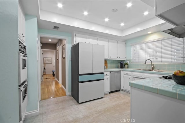 2283 Ximeno Ave, Long Beach, CA 90815 - kitchen featuring stainless steel dishwasher, freestanding refrigerator, a raised ceiling, decorative backsplash, and tile counters