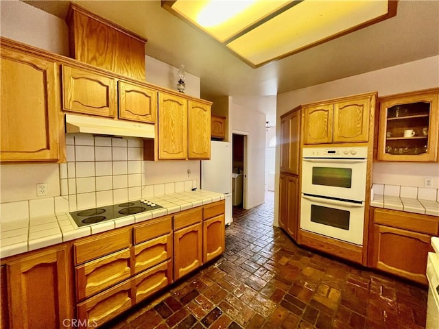 21509 Stage Dr, Tehachapi, CA 93561 - kitchen with white appliances, tile counters, under cabinet range hood, and tasteful backsplash