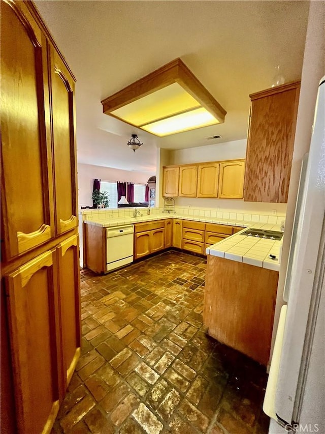 21509 Stage Dr, Tehachapi, CA 93561 - kitchen with white appliances, a peninsula, tile counters, backsplash, and brick flooring