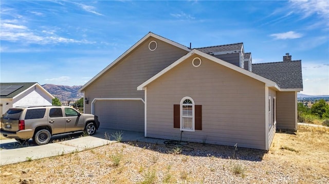21509 Stage Dr, Tehachapi, CA 93561 - view of property exterior with a garage, concrete driveway, a mountain view, and a chimney
