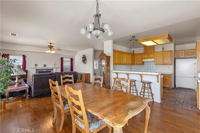 21509 Stage Dr, Tehachapi, CA 93561 - dining room featuring ceiling fan, a brick fireplace, dark wood-style floors, and a chandelier