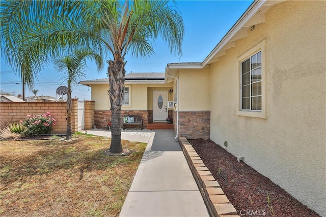 5066 N Nearglen Ave, Covina, CA 91724 - view of exterior entry with stucco siding, roof mounted solar panels, and stone siding