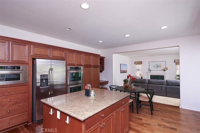 15681 Canon Ln, Chino Hills, CA 91709 - kitchen with appliances with stainless steel finishes, wood finished floors, light stone countertops, a center island, and recessed lighting
