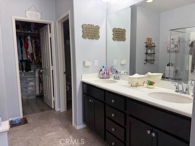 16001 Chase Rd Unit 111, Fontana, CA 92336 - bathroom with double vanity, a walk in closet, a shower stall, and tile patterned floors