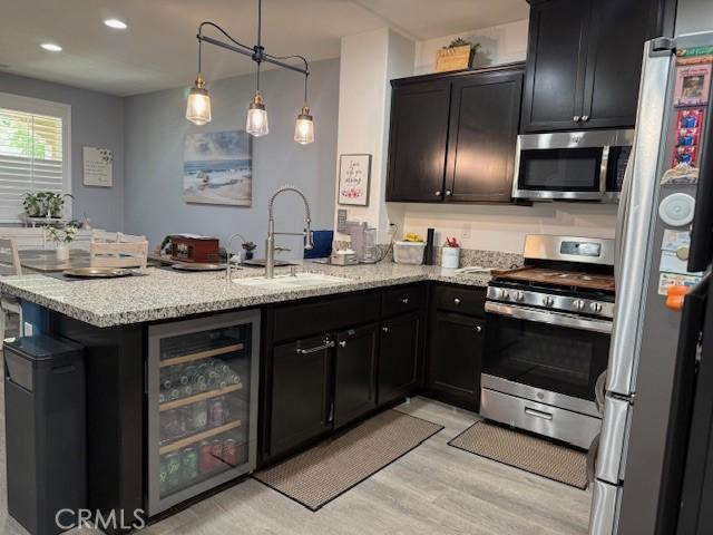 16001 Chase Rd Unit 111, Fontana, CA 92336 - kitchen featuring wine cooler, appliances with stainless steel finishes, a peninsula, light wood-style floors, and light stone countertops