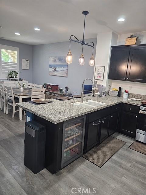 16001 Chase Rd Unit 111, Fontana, CA 92336 - kitchen featuring light stone counters, light wood-type flooring, a peninsula, stainless steel stove, and recessed lighting