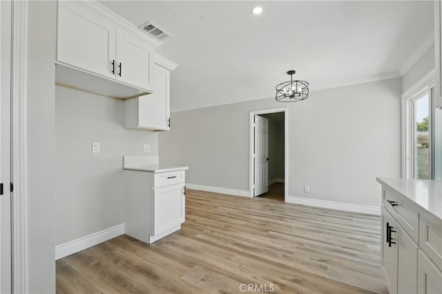 1717 Norval St, Pomona, CA 91766 - kitchen with light countertops, a chandelier, light wood finished floors, white cabinetry, and pendant lighting