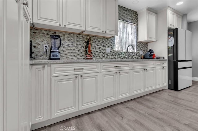 1109 Broadmoor Ave, La Puente, CA 91744 - kitchen with freestanding refrigerator, decorative backsplash, white cabinets, and light wood-type flooring