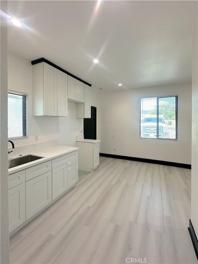 1295 E Whittier Ave, Hemet, CA 92543 - kitchen with light wood-style floors, healthy amount of natural light, white cabinetry, recessed lighting, and light countertops