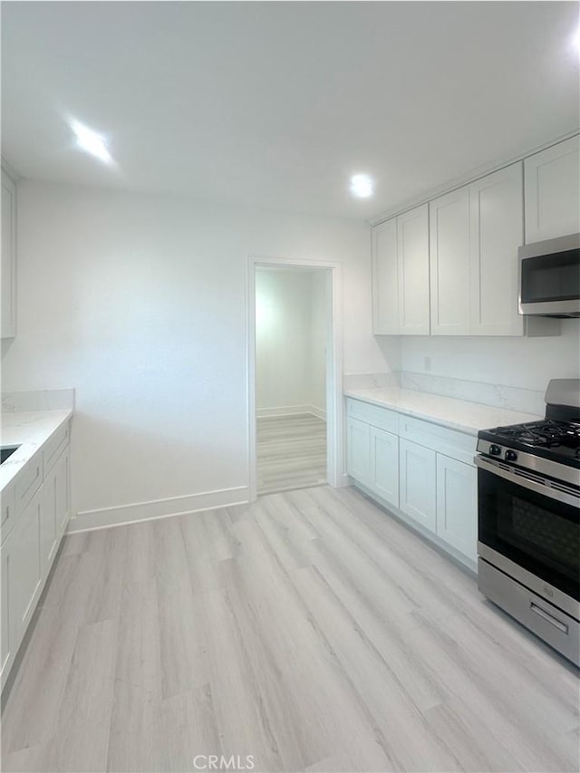 1295 E Whittier Ave, Hemet, CA 92543 - kitchen featuring stainless steel appliances, light wood-style flooring, white cabinets, and light stone counters