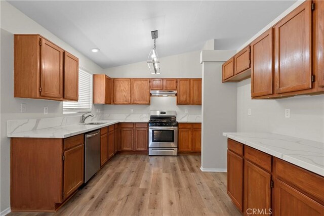 6327 W W Ave J5, Lancaster, CA 93536 - kitchen with stainless steel appliances, brown cabinets, under cabinet range hood, lofted ceiling, and light wood-type flooring