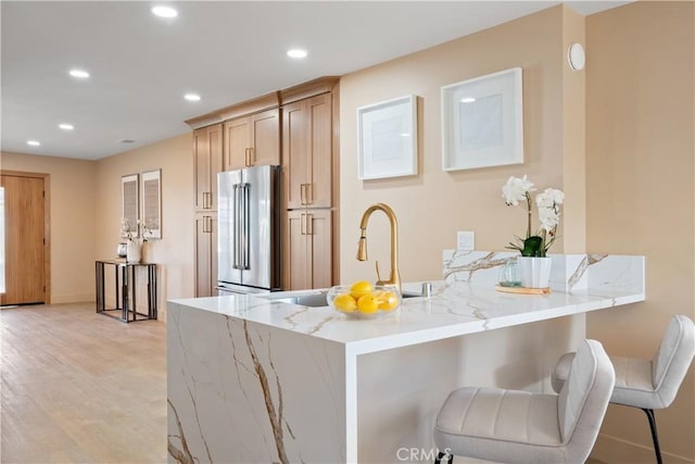 3273 Tilden Ave, Los Angeles, CA 90034 - kitchen with high end refrigerator, light wood-style floors, a breakfast bar area, light stone counters, and recessed lighting