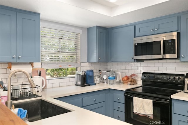 8718 E Indian Hills Rd Unit J, Orange, CA 92869 - kitchen featuring stainless steel microwave, electric range, blue cabinetry, light countertops, and tasteful backsplash
