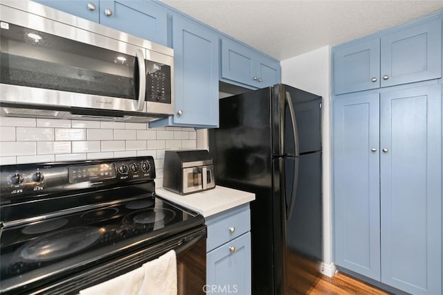 8718 E Indian Hills Rd Unit J, Orange, CA 92869 - kitchen featuring black appliances, blue cabinetry, backsplash, and dark wood-style floors