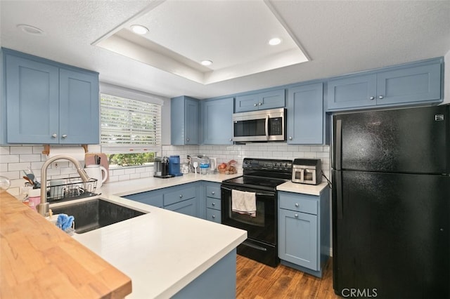 8718 E Indian Hills Rd Unit J, Orange, CA 92869 - kitchen with black appliances, a tray ceiling, dark wood-style floors, blue cabinets, and recessed lighting