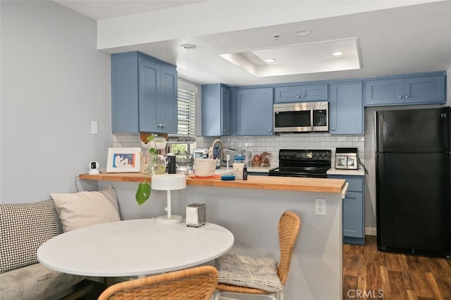 8718 E Indian Hills Rd Unit J, Orange, CA 92869 - kitchen with black appliances, blue cabinetry, a peninsula, dark wood-type flooring, and decorative backsplash