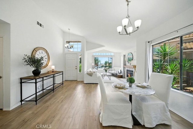 24322 Via Las Junitas, Murrieta, CA 92562 - dining area featuring a chandelier, vaulted ceiling, wood finished floors, and a glass covered fireplace