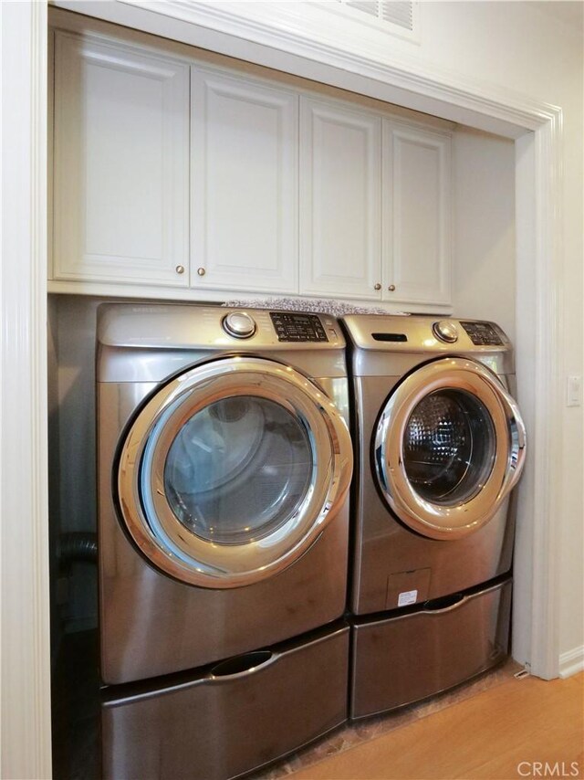 5429 Strand Unit 101, Hawthorne, CA 90250 - laundry room featuring separate washer and dryer, cabinet space, and light wood-style floors