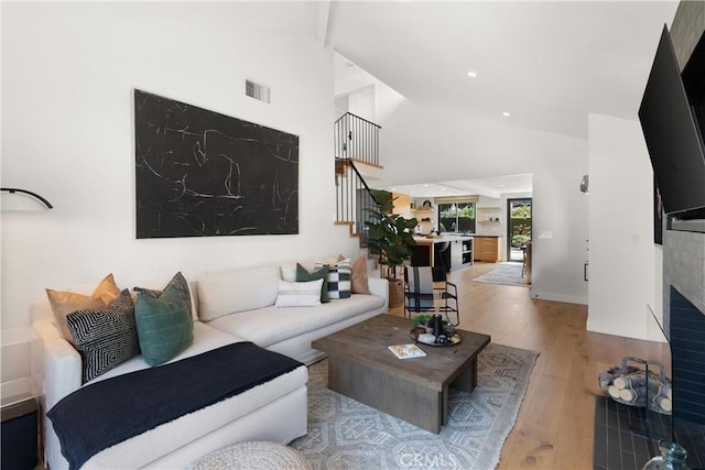 20 Whistling Isle, Irvine, CA 92614 - living room featuring stairs, wood finished floors, high vaulted ceiling, recessed lighting, and a fireplace with flush hearth