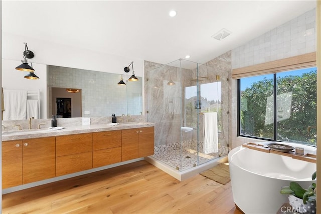20 Whistling Isle, Irvine, CA 92614 - bathroom featuring a soaking tub, double vanity, a shower stall, wood finished floors, and tile walls