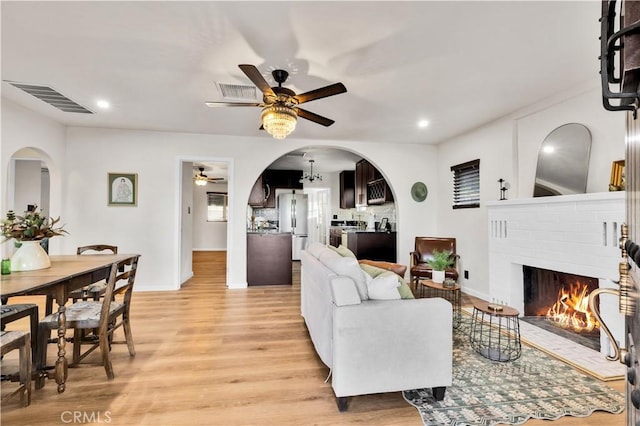 68613 E St, Cathedral City, CA 92234 - living room featuring ceiling fan, light wood-style floors, a brick fireplace, arched walkways, and recessed lighting