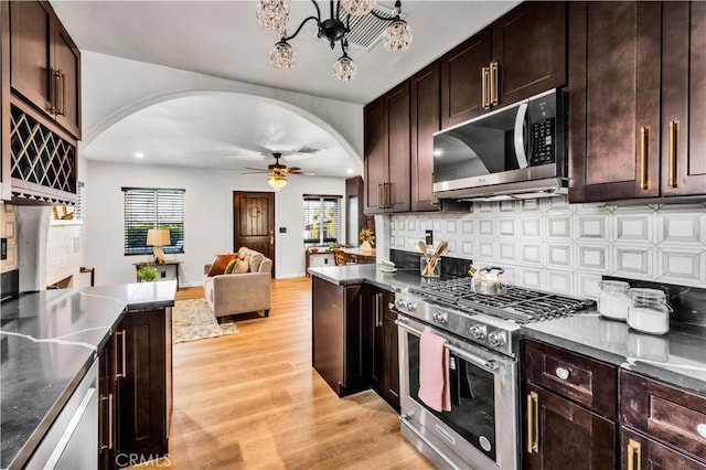 68613 E St, Cathedral City, CA 92234 - kitchen featuring stainless steel appliances, arched walkways, light wood-type flooring, a ceiling fan, and decorative backsplash