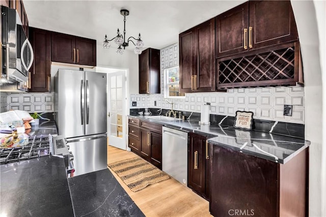 68613 E St, Cathedral City, CA 92234 - kitchen with stainless steel appliances, decorative backsplash, dark brown cabinetry, light wood finished floors, and hanging light fixtures