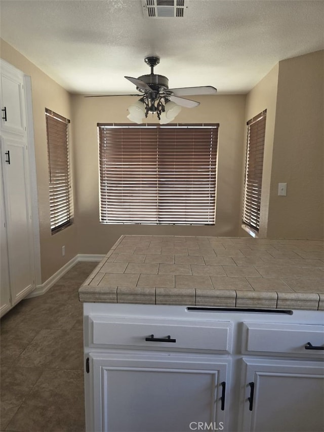 15171 San Jose Dr, Victorville, CA 92394 - kitchen featuring ceiling fan, white cabinetry, tile counters, and a textured ceiling