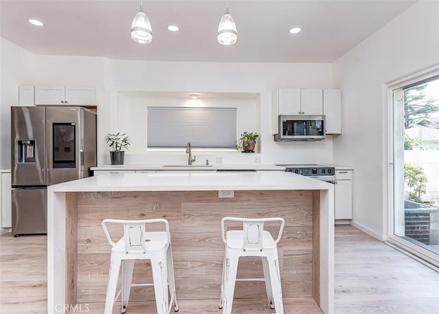 715 S Norton Ave, Los Angeles, CA 90005 - kitchen featuring stainless steel appliances, a breakfast bar, light wood finished floors, light countertops, and a center island