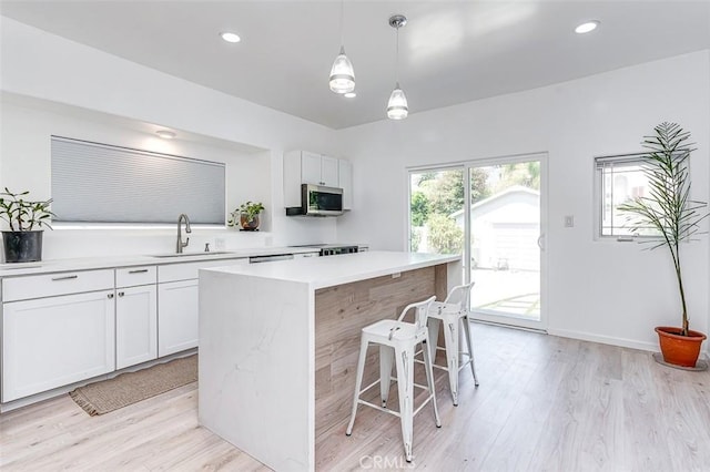 715 S Norton Ave, Los Angeles, CA 90005 - kitchen featuring a kitchen bar, light countertops, light wood-style floors, stainless steel microwave, and recessed lighting