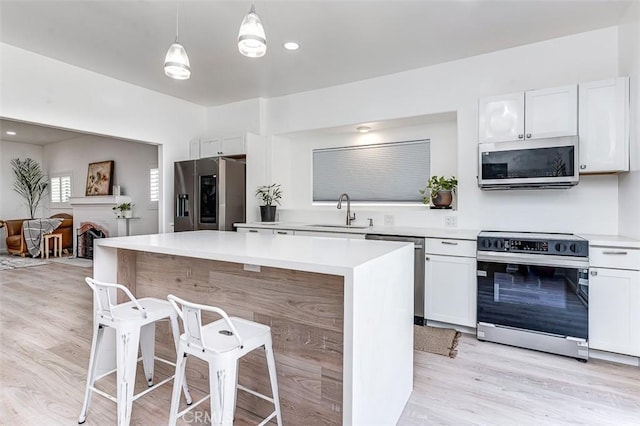 715 S Norton Ave, Los Angeles, CA 90005 - kitchen with appliances with stainless steel finishes, a center island, white cabinets, a kitchen bar, and light countertops