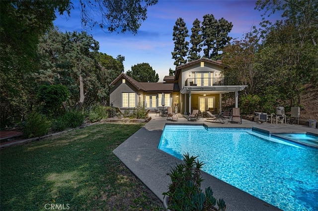 1924 E Rancho Culebra Dr, Covina, CA 91724 - back of property at dusk featuring french doors, a patio area, a balcony, stucco siding, and a lawn