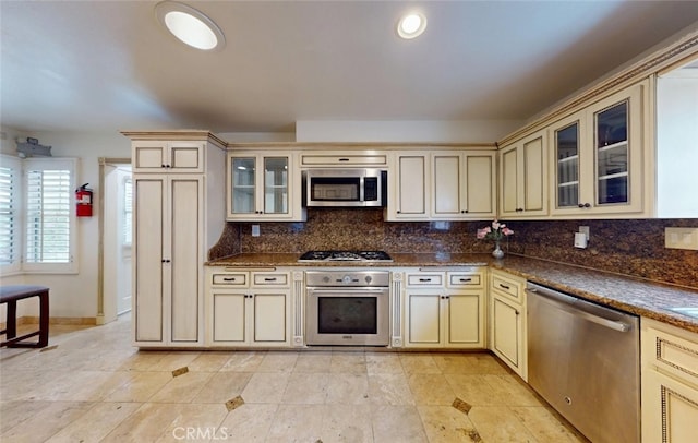 16671 Cedar Cir, Fountain Valley, CA 92708 - kitchen with cream cabinetry, appliances with stainless steel finishes, tasteful backsplash, and dark countertops