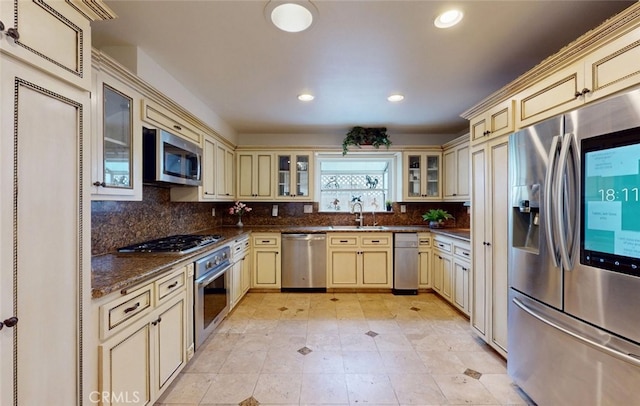 16671 Cedar Cir, Fountain Valley, CA 92708 - kitchen with cream cabinetry, stainless steel appliances, backsplash, recessed lighting, and glass insert cabinets