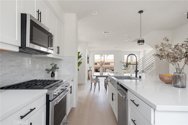 687 W 17th St, Costa Mesa, CA 92627 - kitchen with appliances with stainless steel finishes, light wood-style floors, white cabinetry, tasteful backsplash, and light countertops