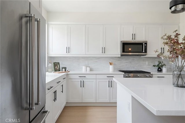 687 W 17th St, Costa Mesa, CA 92627 - kitchen featuring stainless steel appliances, white cabinets, light countertops, decorative backsplash, and light wood-style flooring