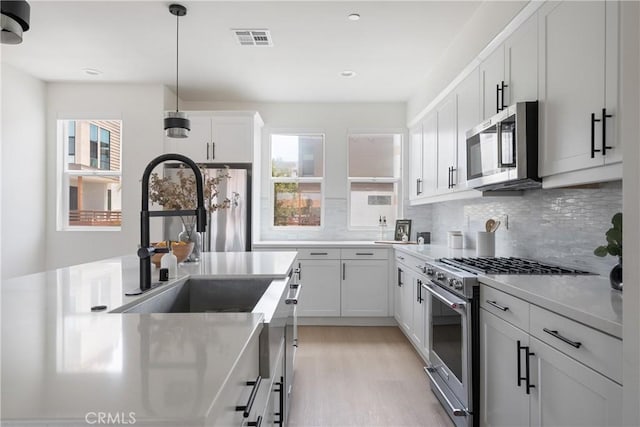 687 W 17th St, Costa Mesa, CA 92627 - kitchen with appliances with stainless steel finishes, healthy amount of natural light, light wood-style floors, decorative backsplash, and recessed lighting