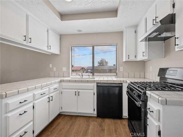 17702 Hinton St, Hesperia, CA 92345 - kitchen with black appliances, under cabinet range hood, a textured ceiling, light wood-type flooring, and white cabinets