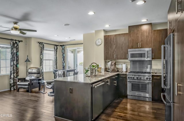 353 American River Ct, Oxnard, CA 93036 - kitchen featuring high end appliances, a peninsula, ceiling fan, dark wood-type flooring, and light stone countertops