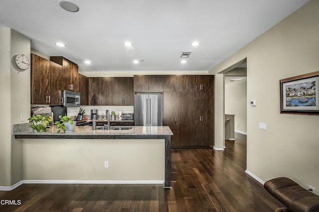 353 American River Ct, Oxnard, CA 93036 - kitchen with appliances with stainless steel finishes, dark brown cabinetry, a peninsula, light stone countertops, and dark wood finished floors
