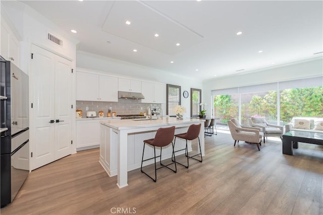 50 Tollson, Irvine, CA 92620 - kitchen with under cabinet range hood, light wood finished floors, decorative backsplash, white cabinets, and recessed lighting