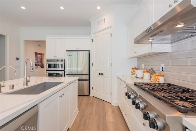 50 Tollson, Irvine, CA 92620 - kitchen with appliances with stainless steel finishes, extractor fan, white cabinets, light wood-style flooring, and backsplash