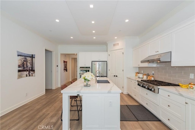 50 Tollson, Irvine, CA 92620 - kitchen featuring appliances with stainless steel finishes, under cabinet range hood, white cabinets, decorative backsplash, and light wood-style floors