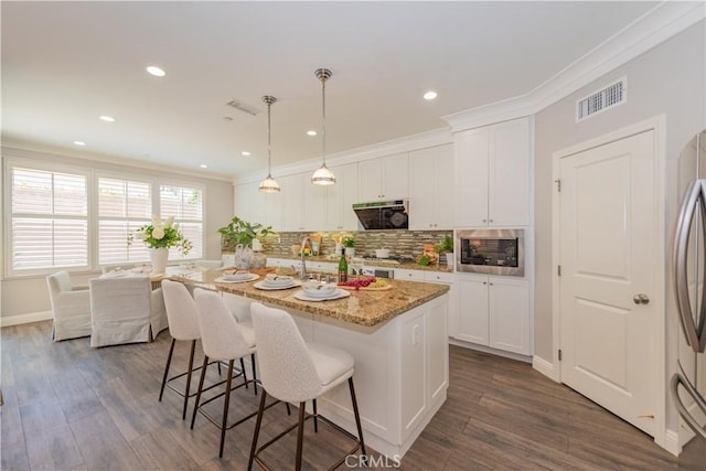 201 Bancroft, Irvine, CA 92620 - kitchen with appliances with stainless steel finishes, a breakfast bar area, decorative backsplash, white cabinetry, and ornamental molding